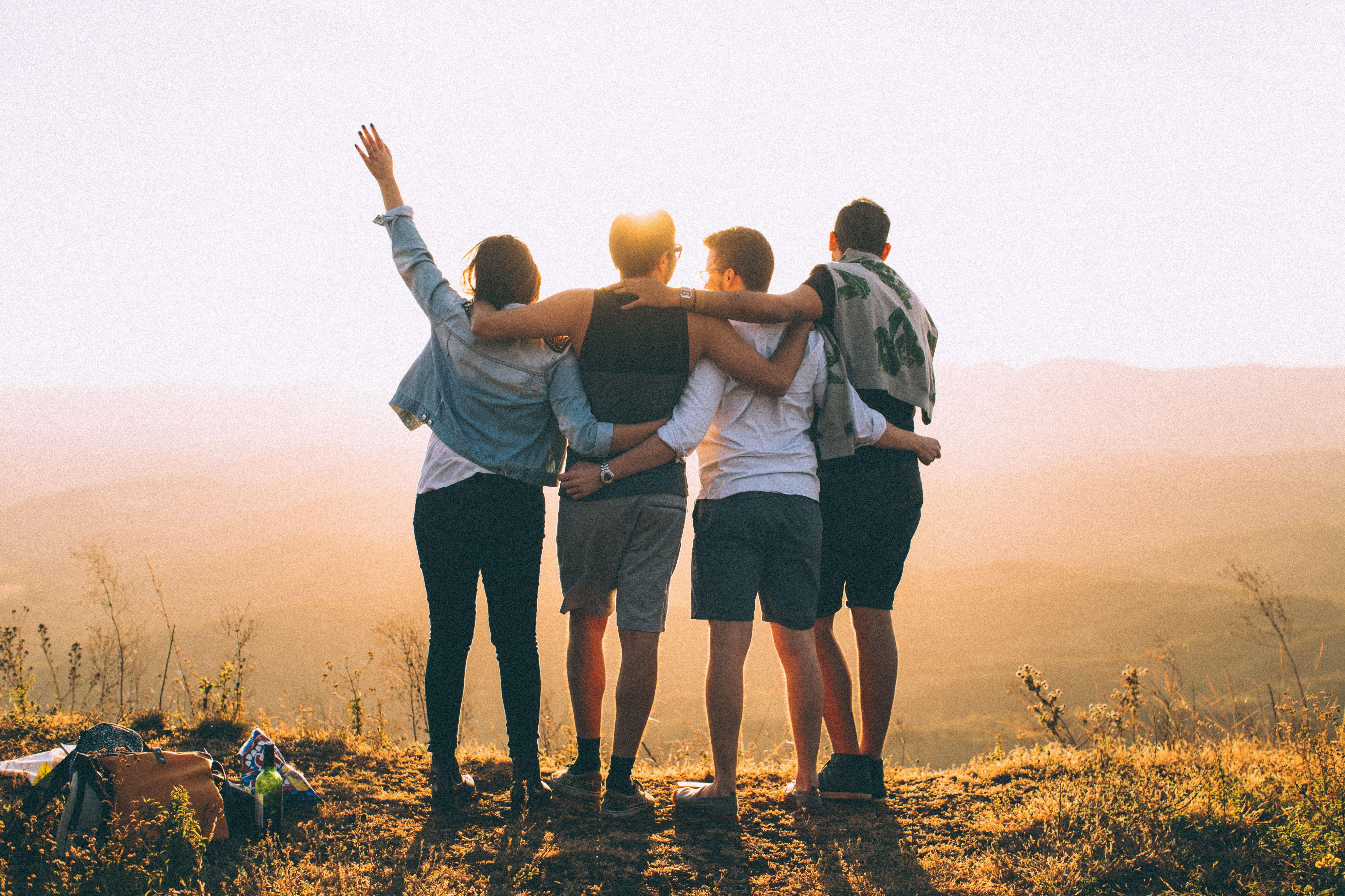 Group of travelers celebrating on a mountain top at sunset